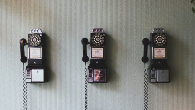 Three vintage rotary payphones mounted on a patterned wall, creating a nostalgic retro communication theme.